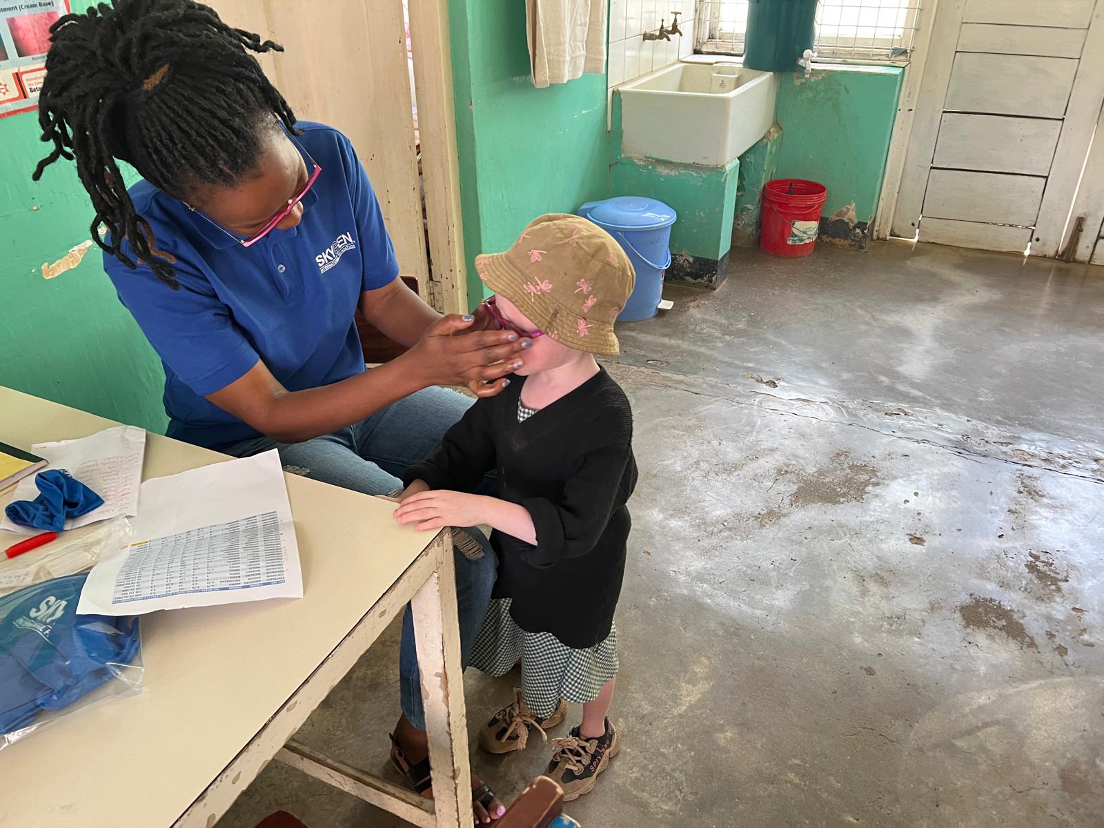A trained health worker carefully fitting eyeglass frames for a child with albinism